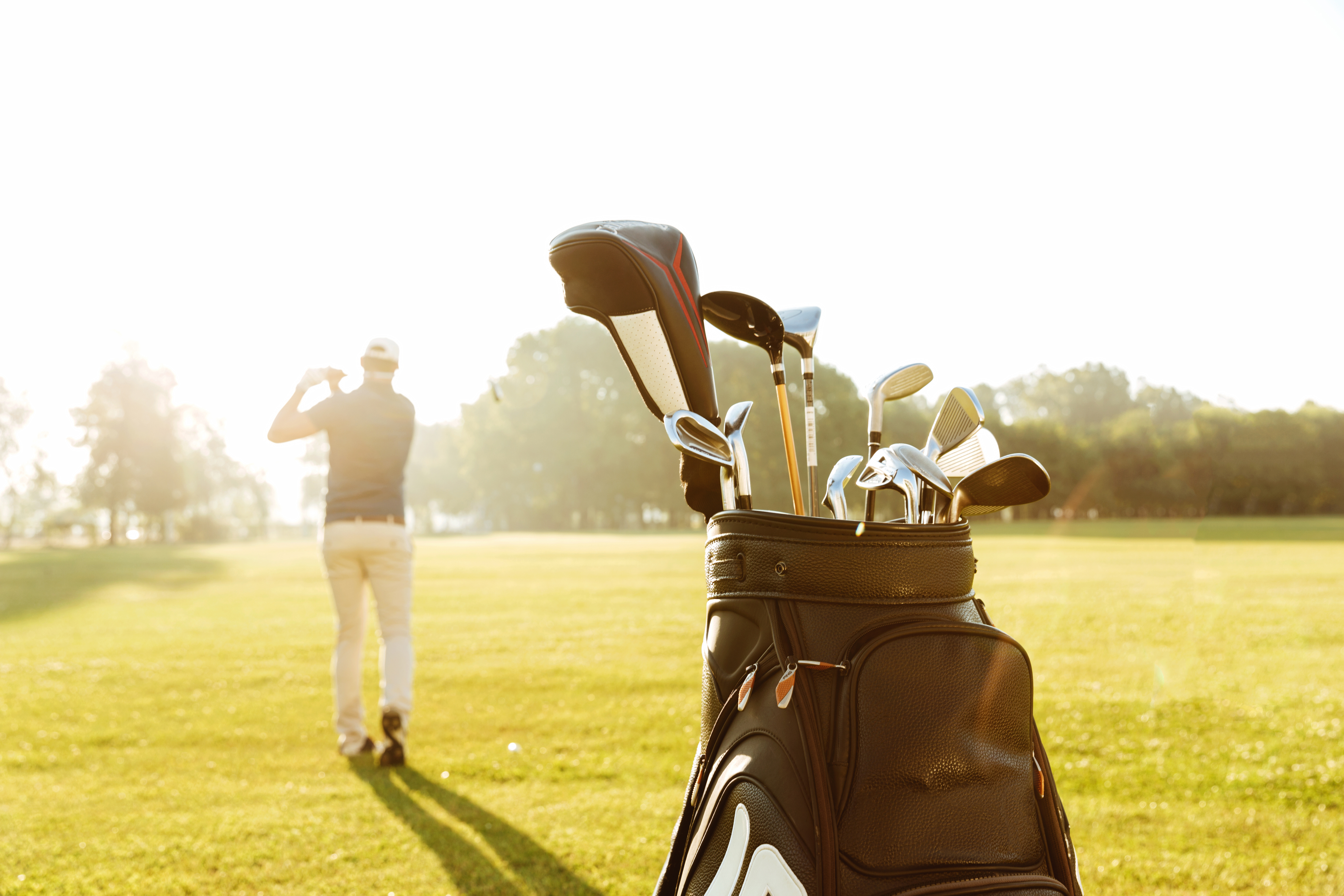 A man on an outdoor golf course using golf clubs fitted for him by Tee Box. 
