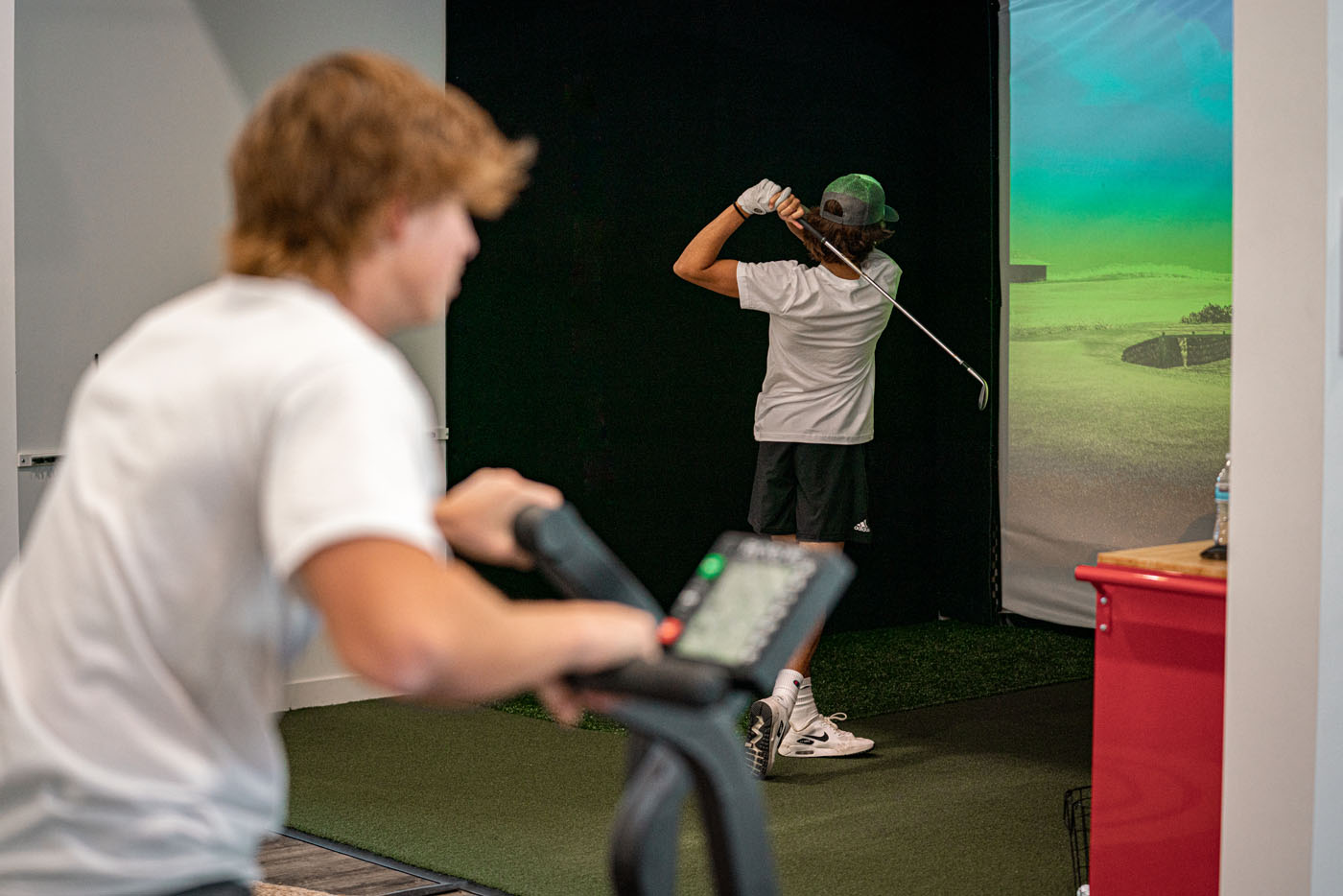 Two young golfers at Tee Box growing their skills using our cutting-edge technology and gym equipment - join our golf camps and youth academy today.