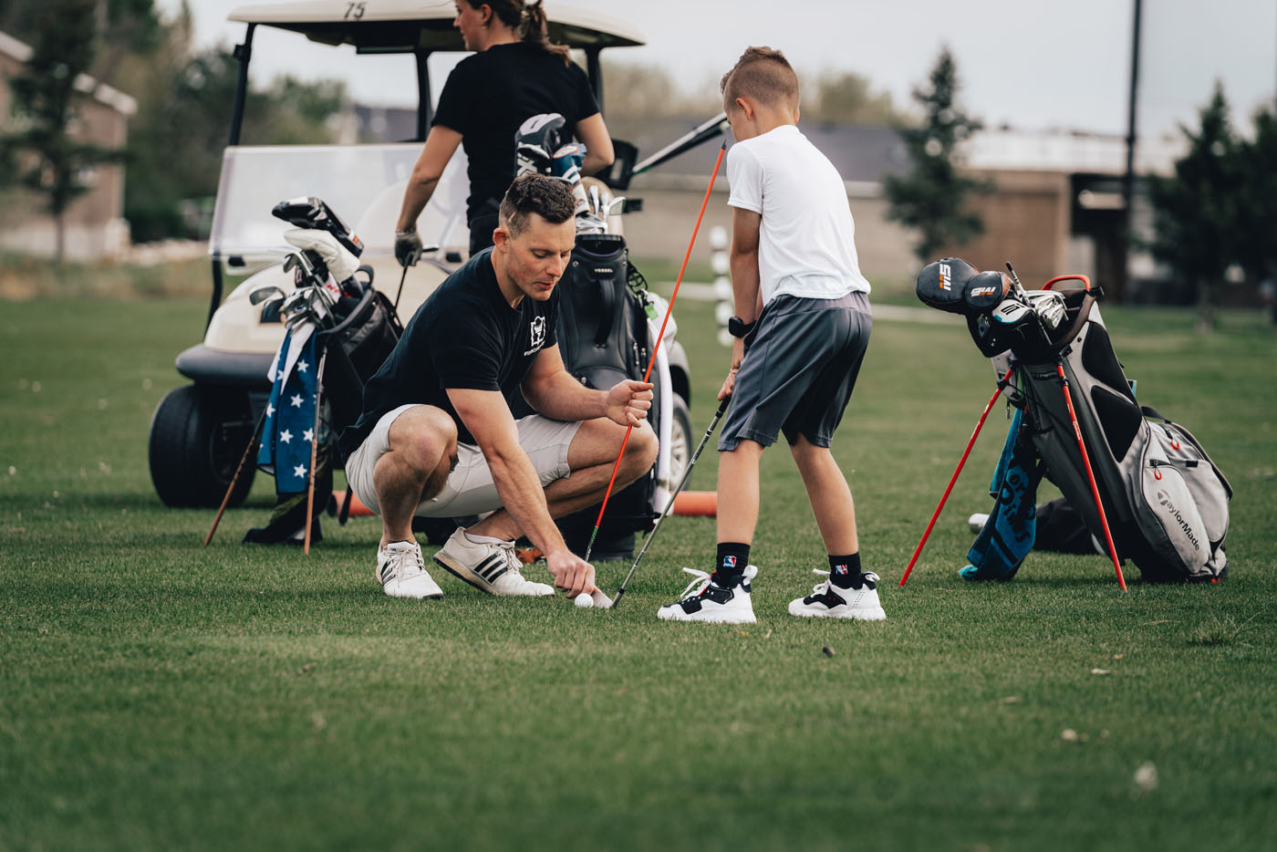A Tee Box employee working with a group of kids on a golf course in McKinney, TX.
